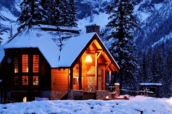 सर्दियों के जंगल के बर्फीले पहाड़ों में एक घर