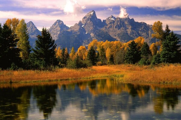 पहाड़ों और जंगलों की पृष्ठभूमि पर झील
