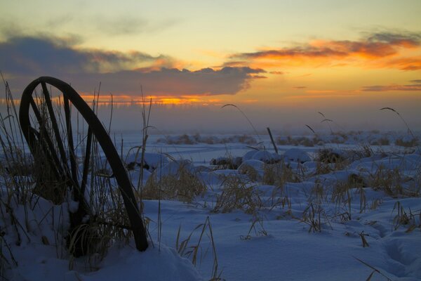 शीतकालीन सूर्यास्त। पनचक्की पानी में जमी हुई है