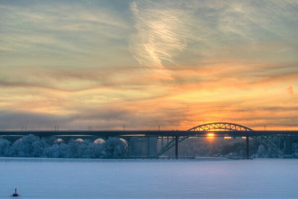 सूर्यास्त की पृष्ठभूमि पर रेलवे पोस्ट। शीतकालीन परिदृश्य